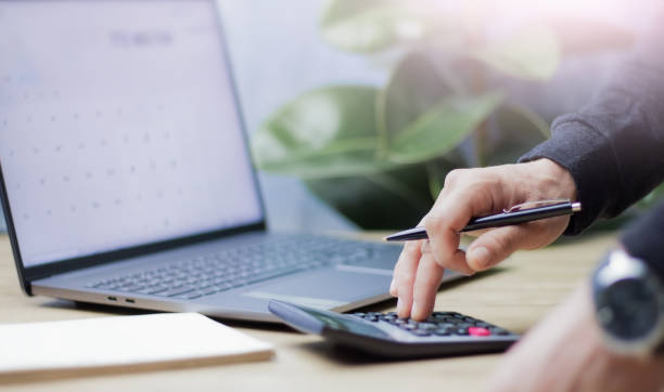 istock Accounting in business, businessman keeps accounting records using calculator, and there is a laptop nearby 2204025534