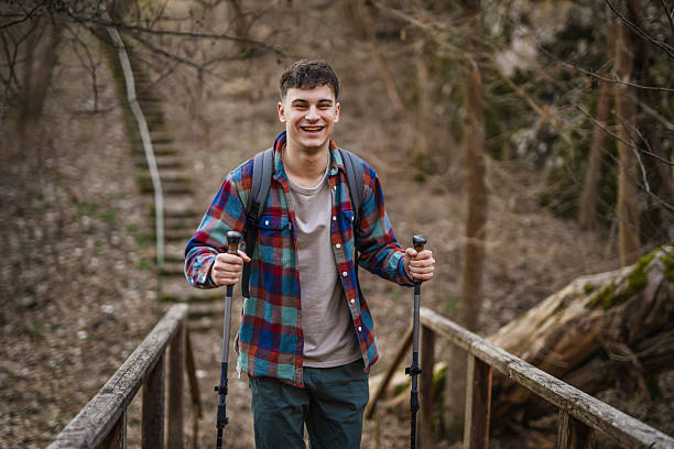 istock Young man hiker backpacker explore scenic forest with hiking sticks 2204025639