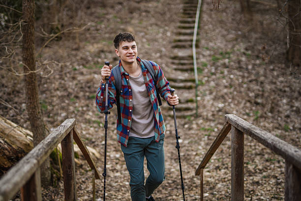 istock Young man hiker backpacker explore scenic forest with hiking sticks 2204025752