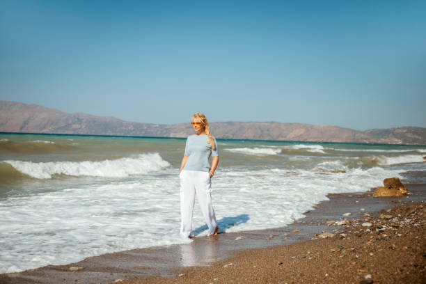 istock Woman walks along the seashore 2204030297