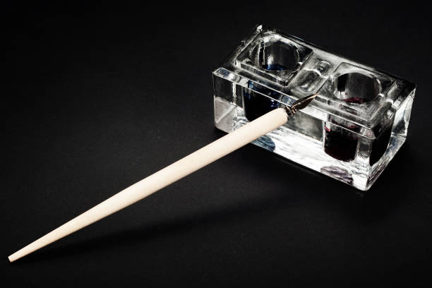 A vintage inkwell and a quill pen on wooden surface