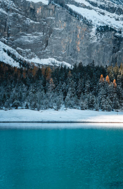 istock Alpine lake, forest and cliffs in fresh snow 2204039078