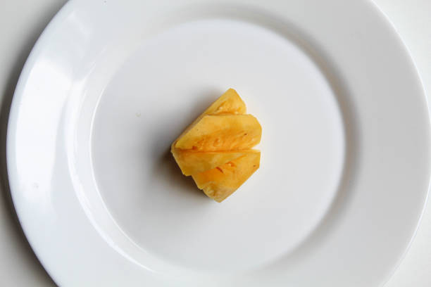 One cut pineapple flesh, on white plate, isolated on white background, flat lay or top view
