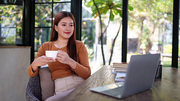 istock Businesswoman holding a coffee cup in a natural-themed office, taking a break from work, relaxing and thoughtful moment. 2204064658