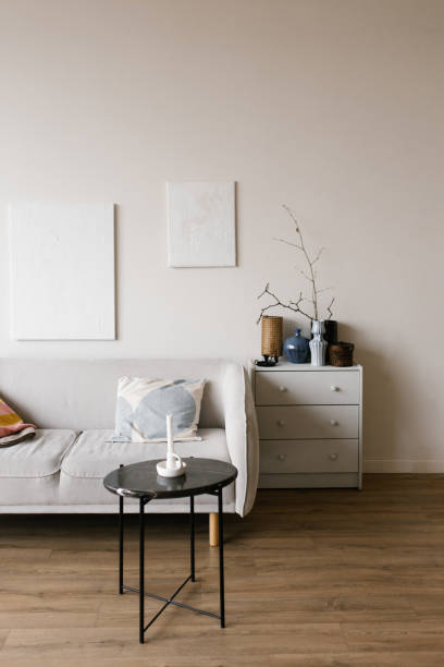 istock Minimalistic modern living room with white wall and couch with blue pillow. lack table with candle on it and vase with branch in it 2204067280