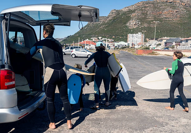 istock Family unloading surfboards for beach surfing adventure 2204070874