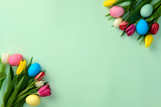 istock Easter eggs with tulip flowers on green background. Flat lay, top view, copy space 2204070886