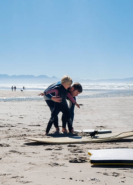 istock Father teaching son to balance on surfboard on beach 2204070960