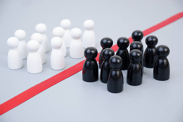 istock Two groups of white and black people figures separated by red line 2204077115