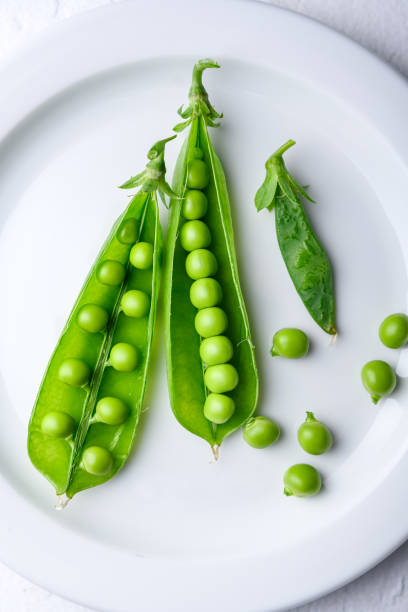 istock Top view of green sugar snap peas on white plate close up 2204088737