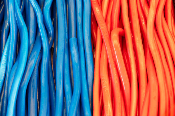 Background of red and green soft candy ropes with glossy smooth surfaces arranged in parallel forming a visually striking contrast of vibrant colors and flexible textures