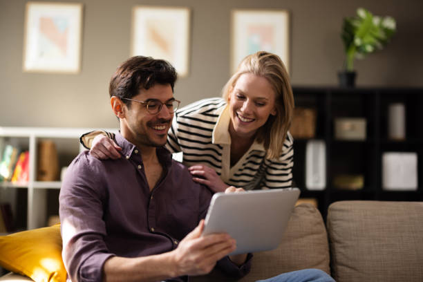 istock Satisfied couple relaxing at home, engaging with a tablet 2204099413