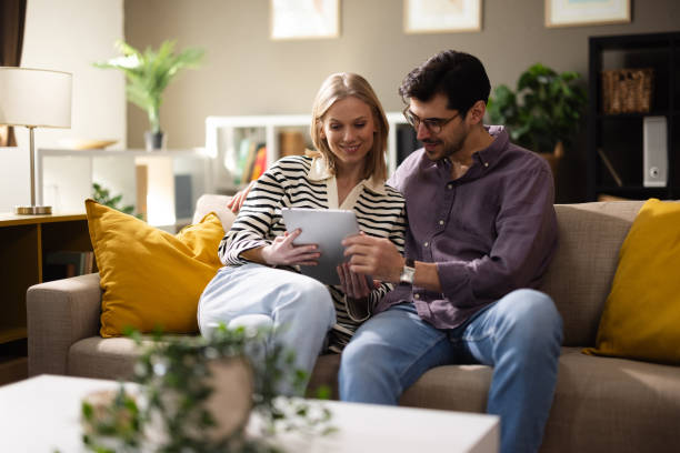 istock Cheerful couple unwinding together on the sofa, using their digital tablet 2204099421