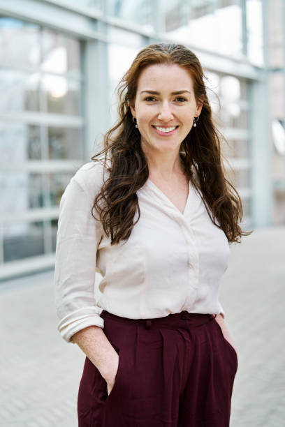 istock Young businesswoman looking at camera with hands in pockets 2204101088