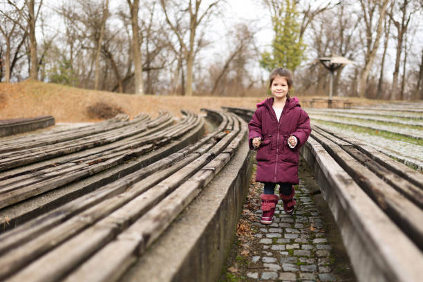A girl walks between the handmade benches of an open-air theater in the forest.
