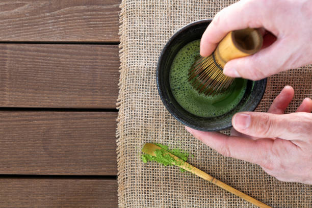 istock man preparing matcha tea with bamboo whisk at wooden table, top view 2204102342