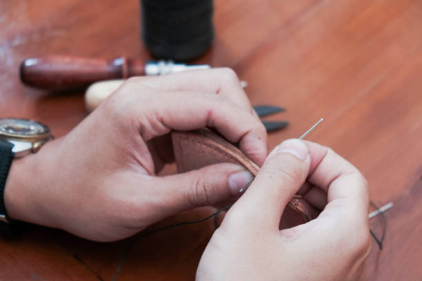 istock A closeup man hand with threads and needle , making leather goods with handstitched process in wooden table 2204102859