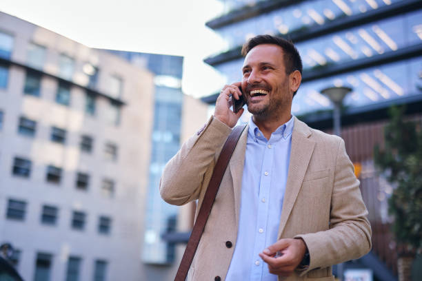 istock Smiling businessman talking on the phone while walking in the city 2204104488