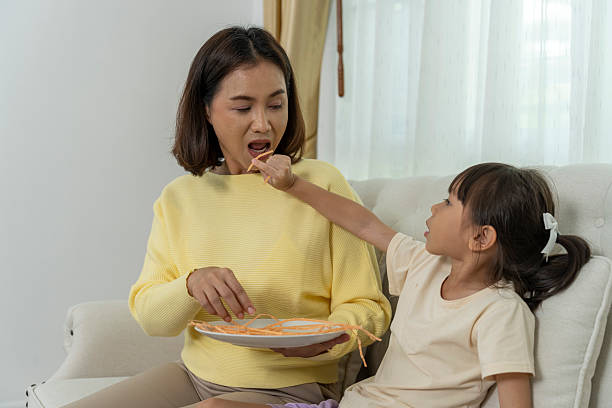 istock Family Bonding Time: Mom and Daughter Sharing a Snack at Home 2204109812