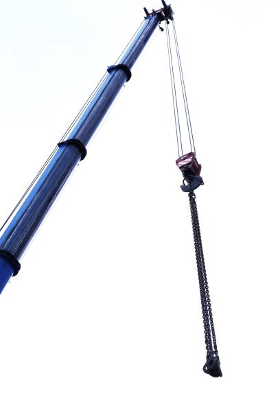 Blue crane arm vertical, boom with hanging hook against clear sky. Construction and lifting heavy building materials, large components and machinery. Construction frame