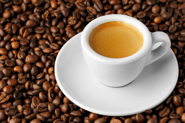 istock Small white espresso cup brimming with fresh, aromatic coffee resting on bed of roasted beans, creating an inviting and visually striking scene 2204113076