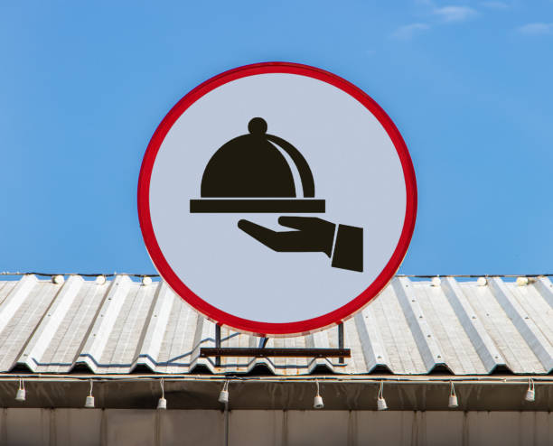 A Circle billboard with icon hand hold cover over food as symbol for restaurant is installed on a roof.