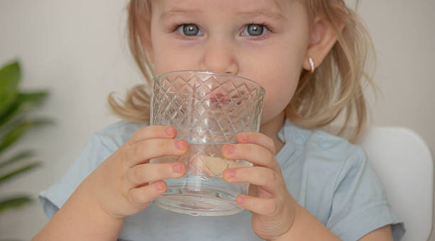 istock little girl drinks water from a glass. Selective focus 2204115781