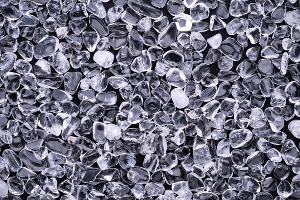 Top view of a stacks of polished clear white Quartz gravel chips on black background