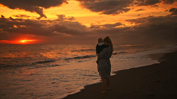 istock Mother and Child Watching Sunset at the Beach 2204120630