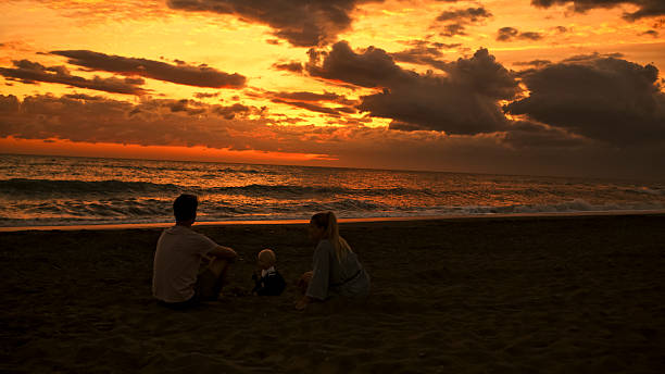 istock Family Sitting on Beach Watching the Sunset 2204120637