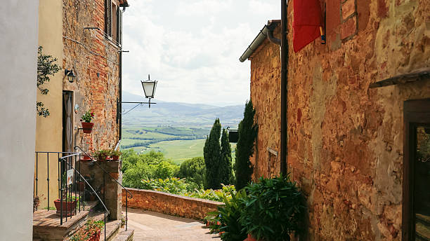 Empty Alley Winds Between Old Town Houses,Opening up to a Breathtaking View of Green Hills in the Distance,The Cloudy Sky Adds a Soft,Moody Touch to the Peaceful Landscape