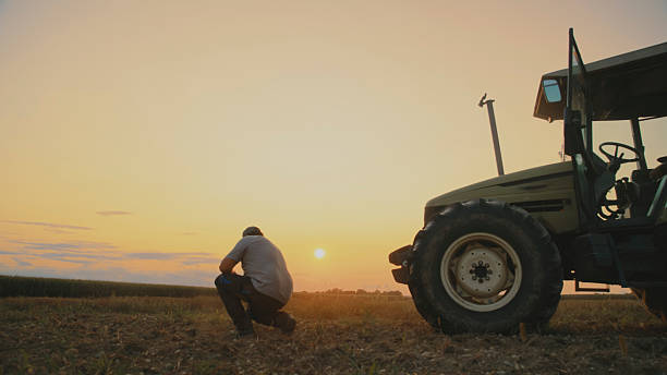 istock Farmer Examines Soil at Sunset for Planting Preparation 2204122741