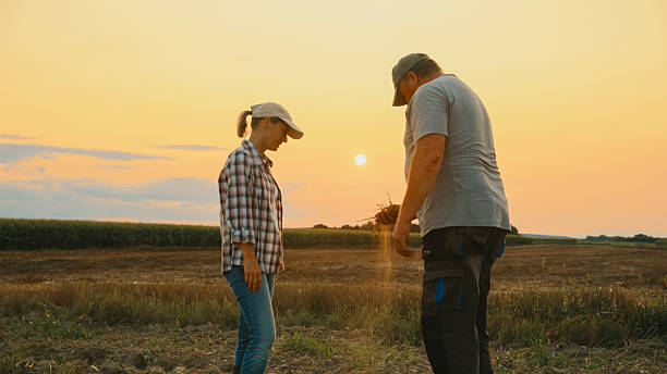 istock Silhouette of Farmers Examining Soil at Sunset 2204122811