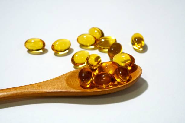 istock Rice bran oil capsule on wooden spoon. 2204124541