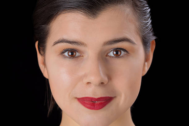 Beautiful face of a smiling pretty woman with big red lips and hazel eyes and clean skin isolated on black background
