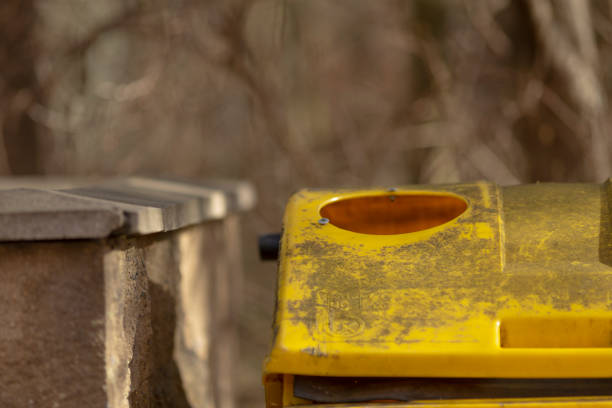 This image features a closeup of a yellow trash can that has a noticeable hole in its structure, which draws attention to its condition
