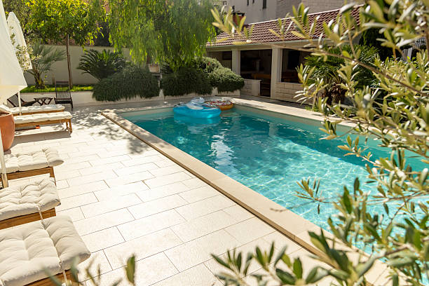 istock Sunny Outdoor Poolside with Cushioned Loungers and Lush Greenery 2204137830