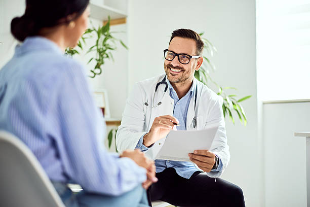 istock Friendly Doctor Consulting Patient in Bright Office During the Day 2204147741
