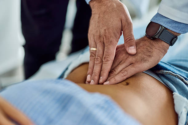 istock Doctor Examining Patient with Hands on Stomach During Medical Checkup 2204147771