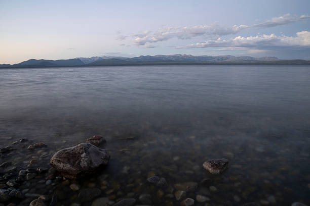Long exposure shot of Nahuel Huapi lake at sunset. Beautiful blurred water effect, the rocky shore and dusk colors.