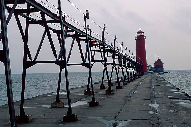 Established in 1839, two lighthouses on the south pier, both painted red, are connected to a lighted catwalk that also connects them to the shore and the Grand Haven Boardwalk.  A huge concrete foundation supports the cylindrical and foghouse outer stands lights.  A magical scene.