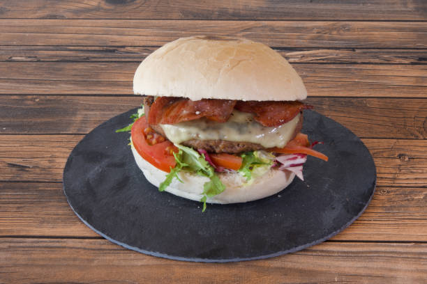 istock A large hamburger with bacon and cheese on a black plate 2204160309