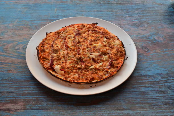 istock A pizza with onions and cheese sits on a white plate on a wooden table 2204160571