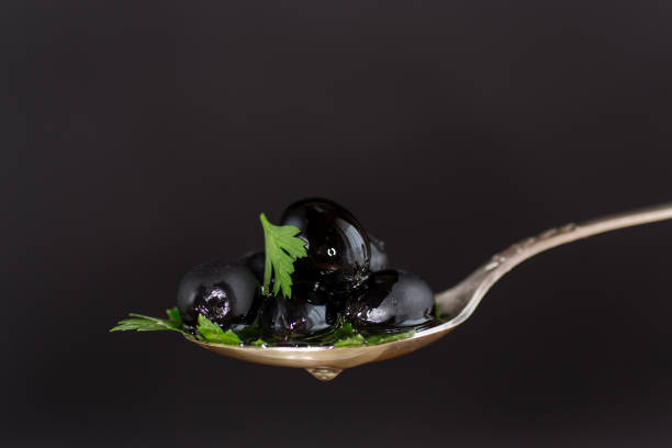 black olives in a spoon isolated on a black background.