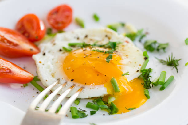 istock Fried eggs with greens and tomatoes on a white plate 2204163655