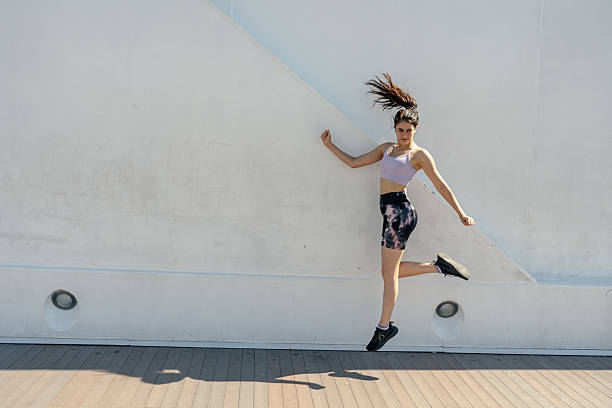 istock Sporty woman jumping and touching a white wall while training outdoors 2204164797