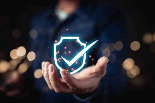 istock A person presenting a glowing blue shield icon with a checkmark, symbolizing cybersecurity, data protection, and trust in secure digital systems within a modern technological framework. 2204167274