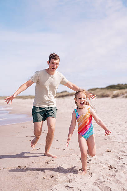 istock Father and daughter playing at coastline 2204167514