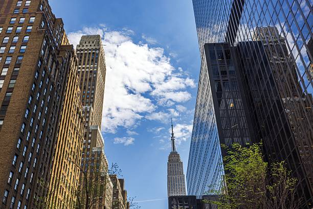 istock Empire State Building framed by modern and historic skyscrapers against blue sky with white clouds. New York. USA. 2204167783