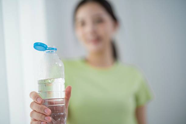 istock Woman holding a water bottle indoors while smiling in natural light during daytime 2204172497